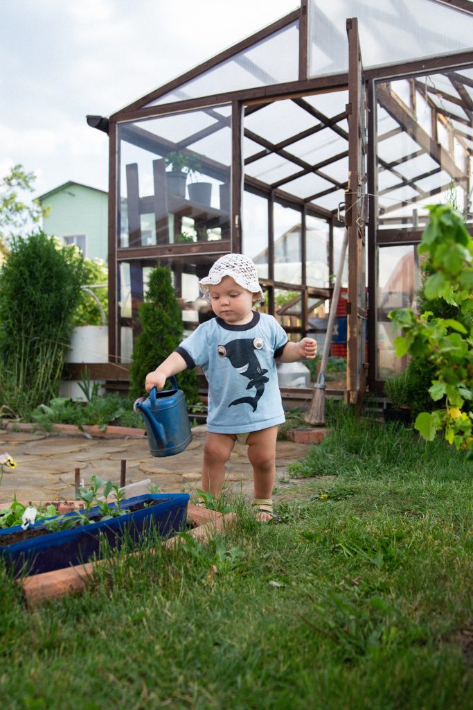 A little girl walks and helps in the garden